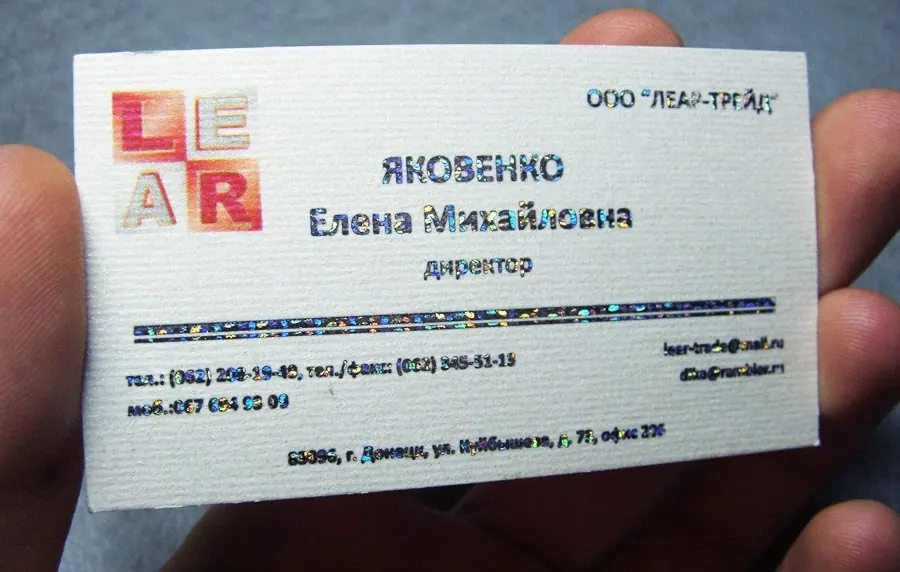 Визитка на белой фактурной бумаге с голографическим тиснением фольгой в руках