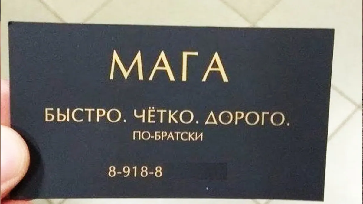 Черная визитная карточка с золотистым текстом в руке человека