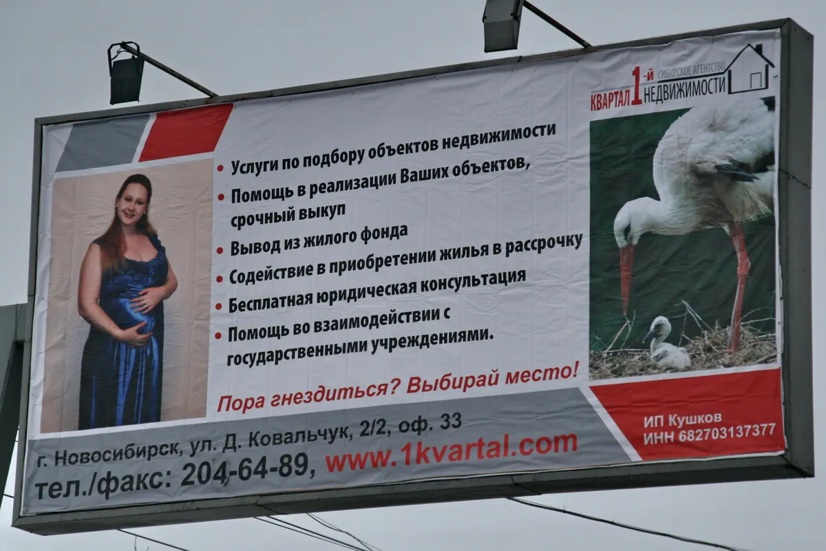 Рекламный щит агентства недвижимости с подробным перечнем услуг и фотографиями
