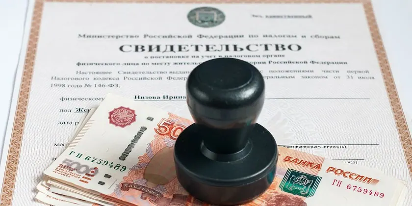 Круглая черная печать и пачка пятитысячных купюр на бланке налогового свидетельства