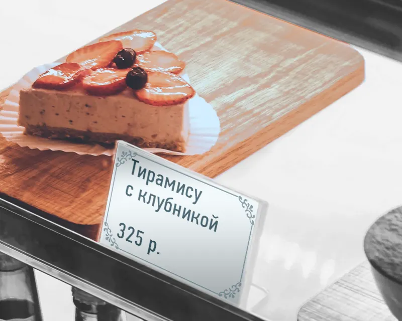 Ценник в прозрачном пластиковом держателе рядом с десертом на витрине кафе