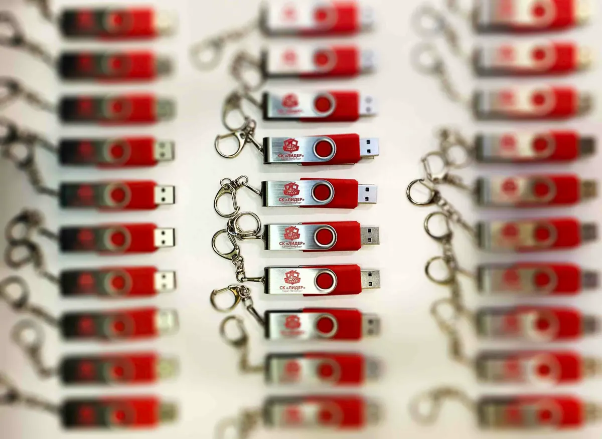 Красные USB-флешки с логотипом в металлическом поворотном корпусе, разложенные рядами